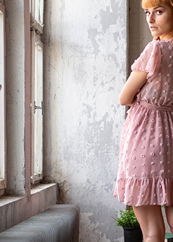Full body portrait of a young woman in a pink dress looking back over her shoulder.