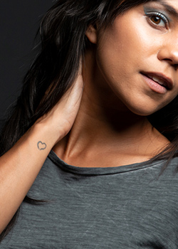 Portrait of a young woman who has a small tattoo in the shape of a heart on her wrist.